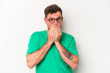 Beyaz arka planda izole edilmiş genç beyaz bir adam ağzı kapalı ve elleri endişeli görünüyor..