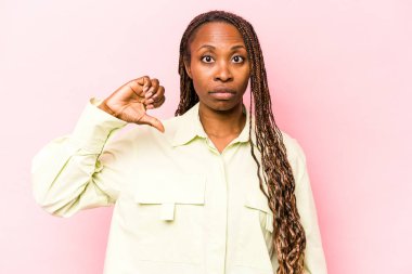 Genç Afro-Amerikalı kadın pembe arka planda izole edilmiş, hoşlanmadığı bir jest gösteriyor, başparmakları aşağıda. Anlaşmazlık konsepti.