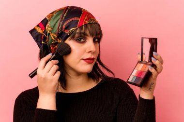 Pembe arka planda göz farı tutan beyaz bir kadın.