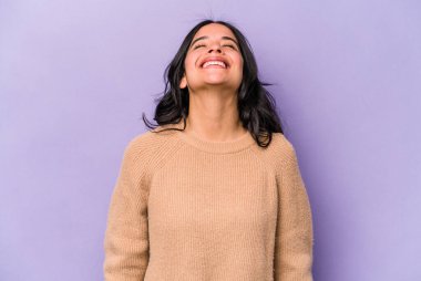 Mor arka planda izole edilmiş genç İspanyol kadın gevşemiş ve mutlu bir şekilde gülüyor, boynunda diş izleri var..