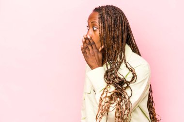 Genç Afrikalı Amerikalı kadın pembe arka planda izole edilmiş. Gördüğü bir şey yüzünden şoka uğruyor..