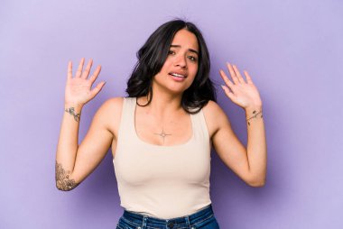 Mor arka planda izole edilmiş genç İspanyol kadın yakın bir tehlike nedeniyle şoka uğruyor.