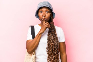 Genç Afrikalı Amerikalı bir kadın pembe arka planda izole bir şekilde kumsala gidiyor ya sır saklıyor ya da sessizlik istiyor..