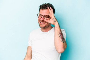 Kafkasyalı genç adam mavi arka planda izole edildi. Heyecanlı görünüyor..