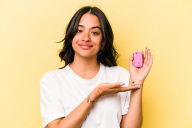 Pembe arka planda izole edilmiş anahtar bir araba tutan genç İspanyol kadın bir avuç içinde fotokopi alanı ve belinde başka bir el tutuyor..