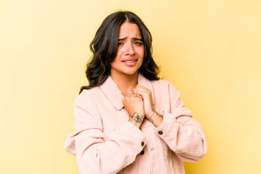 Sarı arka planda izole edilmiş genç İspanyol kadın korkmuş ve korkmuş..