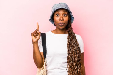 Genç Afrikalı Amerikalı bir kadın pembe arka planda izole edilmiş plaja gidiyor. Harika bir fikri var, yaratıcılık kavramı..