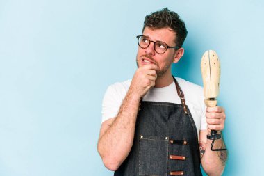 Kafkasyalı genç kunduracı, mavi arka planda izole edilmiş. Bir şeyin fotokopi odasına baktığını düşünerek rahatlamış..