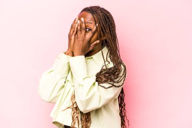 Genç Afrikalı Amerikalı kadın pembe arka planda izole edilmiş. Korkmuş ve gergin parmaklarıyla göz kırp..