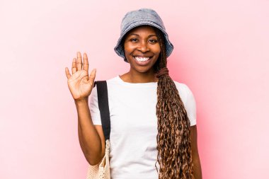 Pembe arka planda izole edilmiş plaja giden genç Afrikalı Amerikalı kadın gülümseyerek beş numarayı parmaklarıyla gösteriyor..
