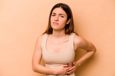 Genç İspanyol kadın bej arka planda izole edilmiş karaciğer ağrısı, mide ağrısı var..