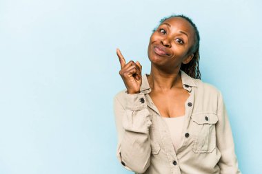 Genç Afrikalı Amerikalı bir kadın mavi arka planda izole edilmiş ve parmağıyla bir numarayı gösteriyor..