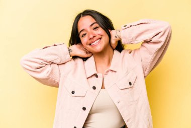 Sarı arka planda izole edilmiş genç İspanyol kadın. Kollarını uzatıyor, rahat duruyor..