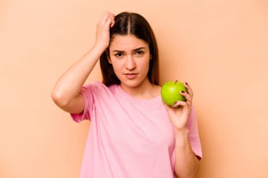 Elinde bej arka planda izole edilmiş bir elma tutan genç İspanyol kadın şok geçiriyordu. Önemli bir toplantıyı hatırladı..