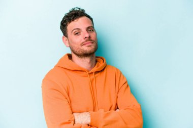 Kafkasyalı genç adam mavi arka planda izole edilmiş şüpheli, belirsiz, seni muayene ediyor..