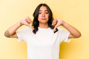 Sarı arka planda izole edilmiş genç İspanyol kadın hoşlanmadığı bir hareket gösteriyor. Anlaşmazlık konsepti.