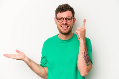 Beyaz arka planda izole edilmiş genç beyaz bir adam elinde bir ürün tutuyor ve.