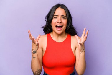 Mor arka planda izole edilmiş genç İspanyol kadın gökyüzüne haykırıyor, yukarı bakıyor, hayal kırıklığına uğramış..