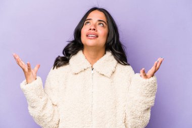 Mor arka planda izole edilmiş genç İspanyol kadın gökyüzüne haykırıyor, yukarı bakıyor, hayal kırıklığına uğramış..