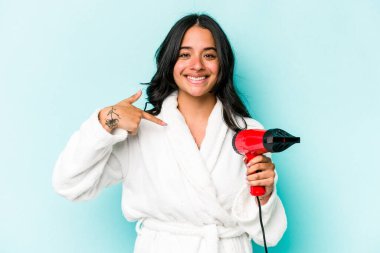 Mavi arka plandaki kurutucuyu tutan genç İspanyol kadın gömlek fotokopi alanını gösteriyor, gururlu ve kendinden emin.