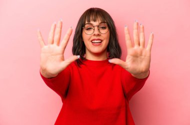 Pembe arka planda izole edilmiş genç beyaz kadın on numarayı elleriyle gösteriyor..