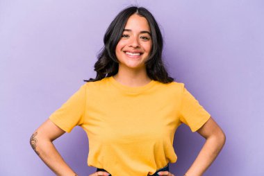 Mor arka planda izole edilmiş genç İspanyol kadın ellerini kalçasından ayırmıyor..