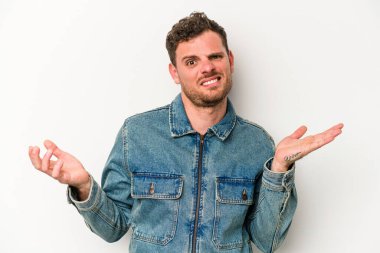 Beyaz arka planda izole edilmiş genç beyaz bir adam sorgulama sırasında omuz silkiyor ve şüphe duyuyor..