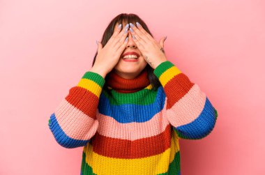 Pembe arka planda soyutlanmış beyaz bir kadın elleriyle gözlerini kapatıyor, büyük bir gülümsemeyle bir sürpriz bekliyor..