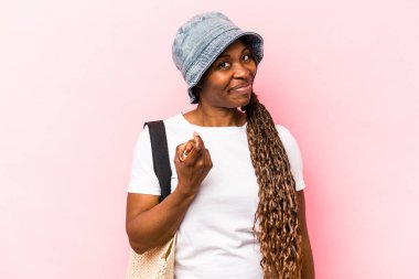 Genç Afrikalı Amerikalı bir kadın pembe arka planda izole bir şekilde kumsala gidiyor. Seni işaret ediyor. Sanki davet ediyormuş gibi..