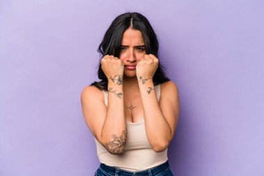 Mor arka planda izole edilmiş genç İspanyol kadın bir tartışma yüzünden yumruk, öfke, kavga ve boks atıyor..