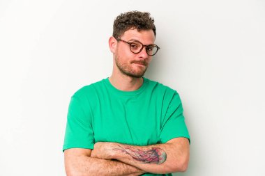 Beyaz arka planda izole edilmiş genç beyaz adam alaycı bir ifadeyle kameraya bakıyor..