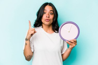 Mavi arka planda bir saat tutan genç İspanyol kadının bir fikri, ilham konsepti var..