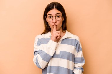 Genç İspanyol kadın bej arka planda izole edilmiş bir şekilde bir sır saklıyor ya da sessizlik istiyor..