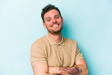 Mavi arka planda izole edilmiş genç beyaz adam mutlu, güler yüzlü ve neşeli.