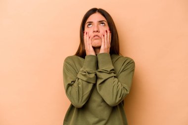 Latin kökenli genç bir kadın, bej arka planda izole edilmiş, sızlanıyor ve ağlıyordu..