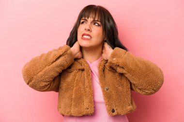 Genç, beyaz bir kadın pembe arka planda izole edilmiş. Durağan yaşam tarzından dolayı boyun ağrısı çekiyor..