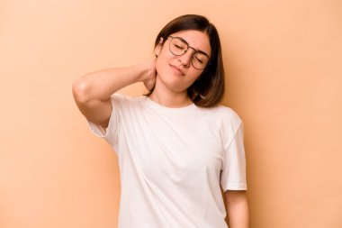 Genç İspanyol kadın bej arka planda izole edilmiş. Dirsek masajı yapıyor. Kötü bir hareketin ardından acı çekiyor..