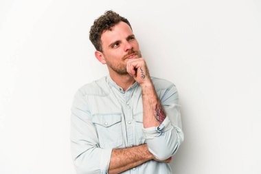 Beyaz arka planda soyutlanmış genç beyaz bir adam düşünüyor ve yukarı bakıyor, yansıtıyor, düşünüyor, hayal kuruyor..