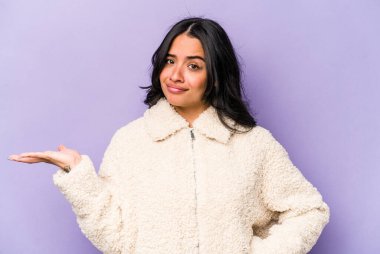 Mor arka planda izole edilmiş genç İspanyol kadın sorgulama sırasında omuz silkiyor ve şüphe duyuyor..