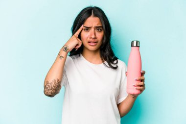 Mavi arka planda termometreyi tutan genç İspanyol kadın işaret parmağıyla hayal kırıklığı gösteriyor..