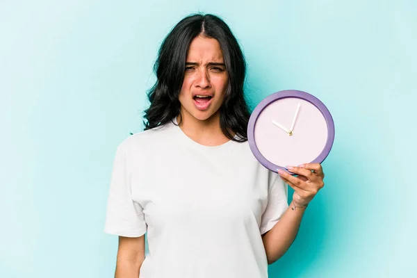 Young Hispanic Woman Holding Clock Isolated Blue Background Screaming Very — Stok fotoğraf