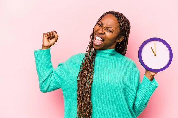 Ung Afroamerikansk Kvinna Håller Klocka Isolerad Rosa Bakgrund Höja Näve — Stockfoto