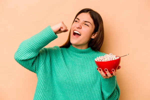 Young Hispanic Woman Eating Cereals Isolated Beige Background Raising Fist — Stock Photo, Image