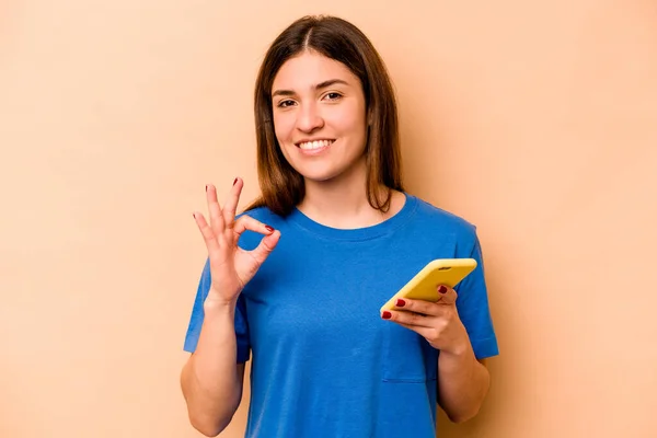 Νεαρή Καυκάσια Γυναίκα Κρατώντας Κινητό Τηλέφωνο Απομονώνονται Μπεζ Φόντο Χαρούμενα — Φωτογραφία Αρχείου