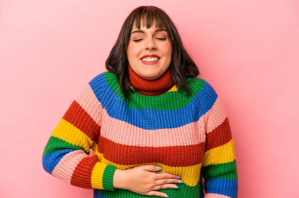 Genç beyaz kadın pembe arka planda izole edilmiş karnına dokunuyor, nazikçe gülümsüyor, yemek yiyor ve tatmin oluyor..