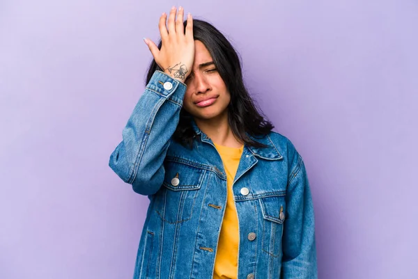 Mor arka planda izole edilmiş genç İspanyol kadın bir şeyi unutuyor. Alnına avuç içi ile vuruyor ve gözlerini kapıyor..