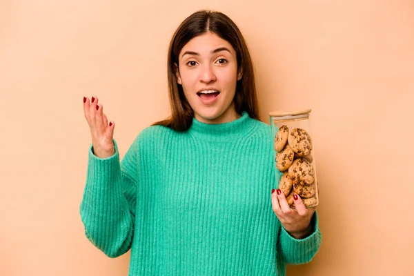 Молода Іспаномовна Жінка Тримає Банку Печива Ізольовані Бежевому Фоні Отримує — стокове фото