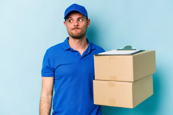 Young Caucasian Delivery Man Isolated Blue Background Confused Feels Doubtful — Stockfoto