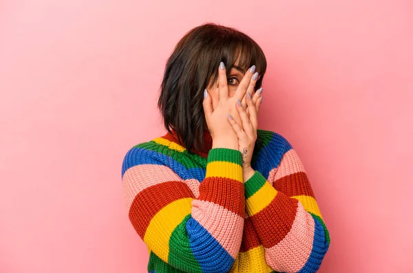 Pembe arka planda izole edilmiş genç beyaz kadın parmaklarıyla gözünü kırp korkmuş ve gergin..