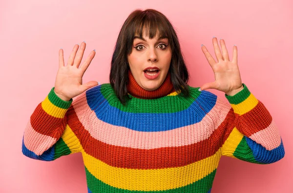 Pembe arka planda izole edilmiş genç beyaz kadın hoş bir sürpriz alıyor, heyecanlı ve el kaldırıyor..